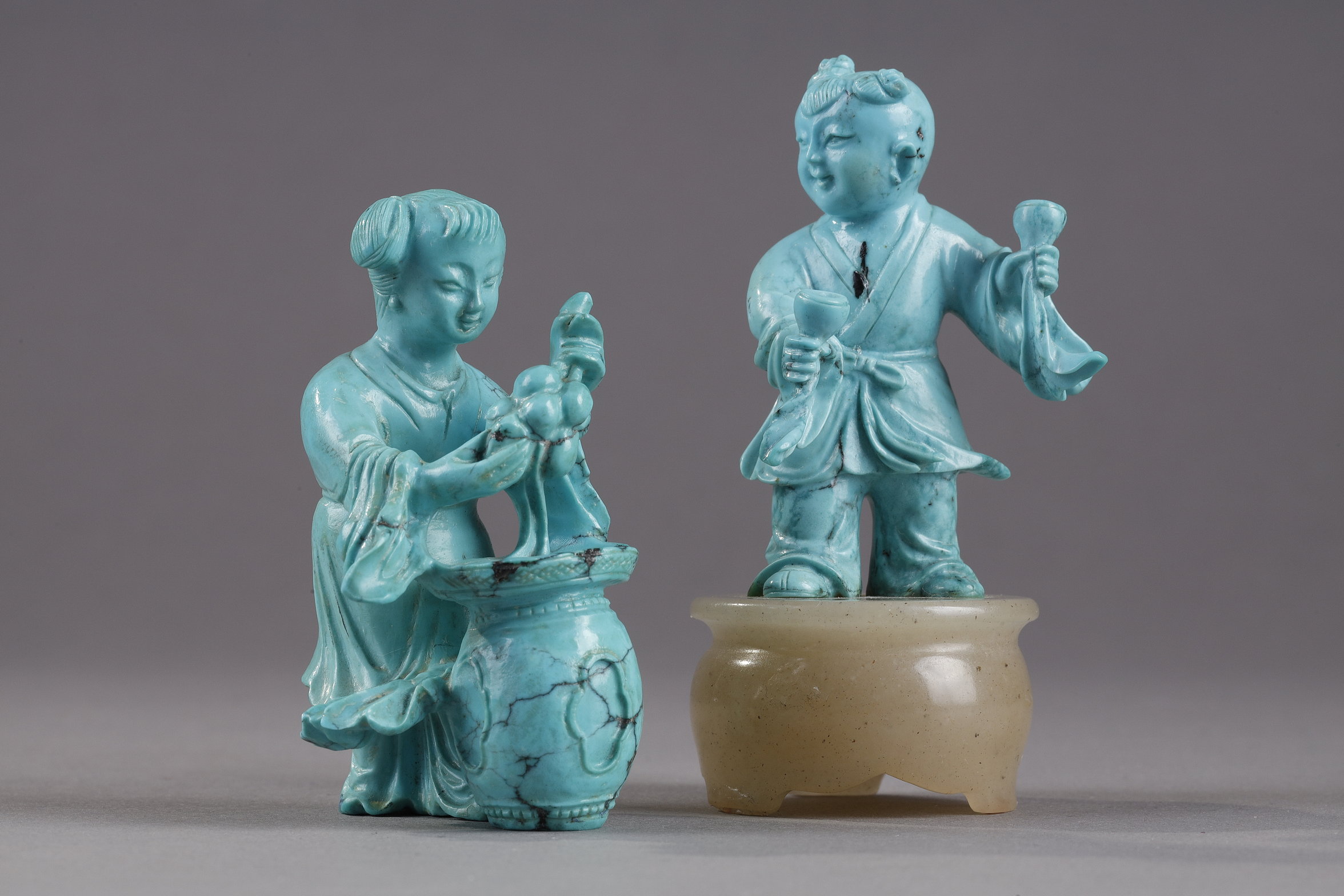 Finely carved turquoise statuettes - China Qing period circa 1900
1)Depicting a young woman pressing fruit on a tray on a barrel-shaped stool 
2) representing a child on a soapstone base 